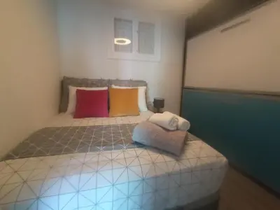 a small bedroom with a bed with colorful pillows at Cullera Buena Vista Social Club con piscina y vistas al mar Solo Familias! in Cullera