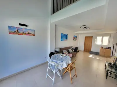 a living room with a table and a couch at Luminoso ático dúplex con terraza de césped in Montroy