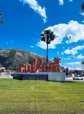 a sign in a park with a palm tree and a mountain at Apartamento primera línea playa San Antonio in Cullera