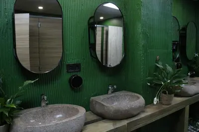 a green bathroom with two sinks and two mirrors at The POD Suite Hostel Village in Valencia