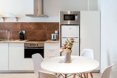 a white kitchen with a white table and white chairs at Ruzafa´s Gate 3 in Valencia
