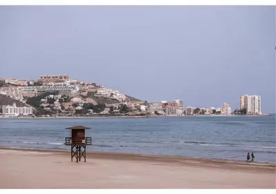 a lifeguard stand on a beach with a city in the background at El balcón del mar - 1ª línea y frontal al mar in Cullera