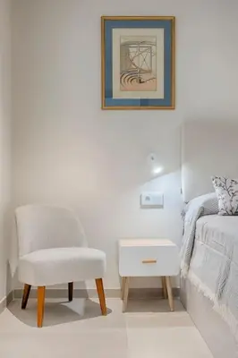 a white bedroom with a chair and a bed at Portal de Ruzafa 4 in Valencia