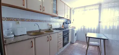 a kitchen with white cabinets and a sink and a stove at Vacansis Sant Germein in Cullera