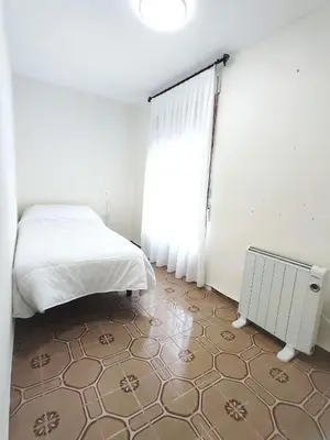a white bedroom with a bed and a window at Apartamentos rurales Villamalur in Villamalur