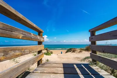 a wooden pathway to a beach with the ocean at Apartamento cerca de la playa in Cullera