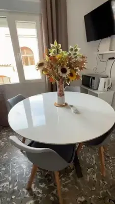 a white table with a vase of flowers on it at Apartamento cerca de la playa in Cullera