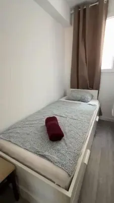 a small bed with a red pillow on it at Apartamento cerca de la playa in Cullera