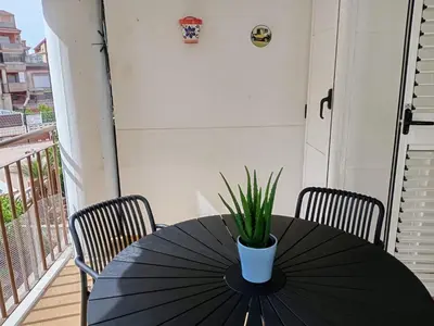 a black table with a potted plant on a balcony at Apartamento playa de Canet WIFI in Canet de Berenguer