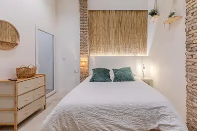 a bedroom with a white bed and a wooden dresser at GREEN&FRESH Apartament in Valencia