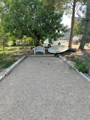 a bench and a surfboard in a gravel parking lot at El Refujio maison independante avec vraie piscine privée au sel chauffee pas de chlore in Turís