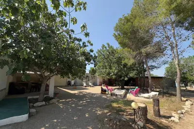a yard with chairs and tables and trees at El Refujio maison independante avec vraie piscine privée au sel chauffee pas de chlore in Turís