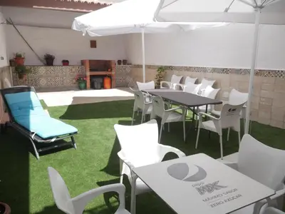 a patio with white tables and chairs and grass at Casa Vistalmar in Cullera