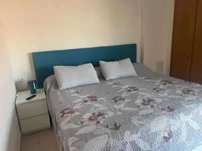 a bed with a blue headboard and two pillows on it at APARTAMENTO Playa Patacona VALENCIA in Valencia