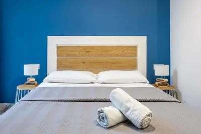 a bedroom with a large bed with a blue wall at New Apartment 1 ROOM,4 pax,wifi, ACRuzafa market in Valencia