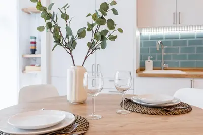 a wooden table with plates and glasses and a vase at Julio's Apartment in Valencia