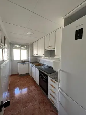 a kitchen with white cabinets and a white refrigerator at Caballito de Mar in Tavernes de Valldigna
