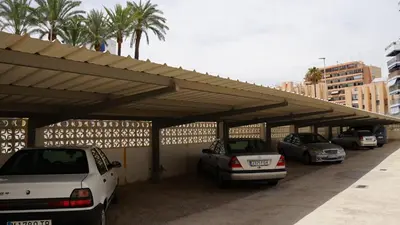 a parking lot with cars parked under a roof at Apartamento en complejo residencial con piscina in Puebla de Farnals