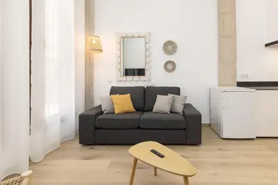 a living room with a gray couch and a mirror at ApartUP Ca La Leni Beach I in Valencia