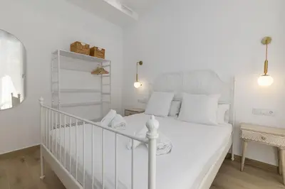 a white bedroom with a white bed with white pillows at ApartUP Ca La Leni Beach II in Valencia