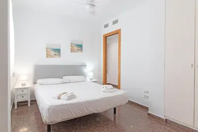 a white bedroom with a bed and a mirror at Global Vacacional, Bonito apartamento en Puerto de Sagunto cerca de la playa in Puerto de Sagunto