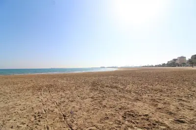 a sandy beach with the ocean in the background at Global Vacacional, Bonito apartamento en Puerto de Sagunto cerca de la playa in Puerto de Sagunto
