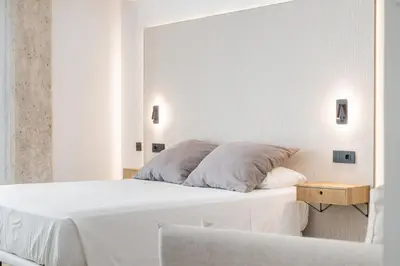 a white bedroom with a bed and a table at Guastavino by Alma Suites in Valencia