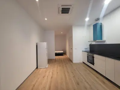 an empty kitchen with a refrigerator and wooden floors at Apartamento Cienciasmar in Valencia