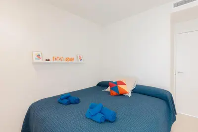 a bedroom with a bed with blue slippers on it at Terrasses - Beach apartment with swimming pool in Puzol