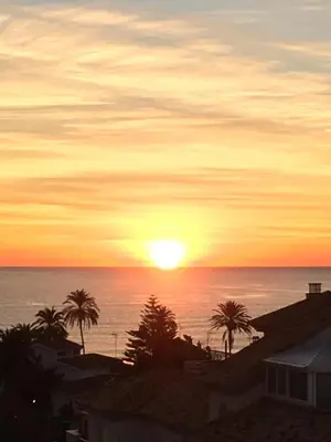 a sunset over the ocean with palm trees at Panorama Azul Apartment in El Puig