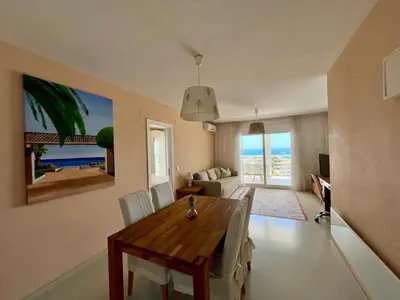 a dining room with a table and a living room with the ocean at Panorama Azul Apartment in El Puig