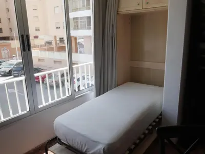 a bed in a room with a large window at Malvarrosa, 1-6 in Cullera