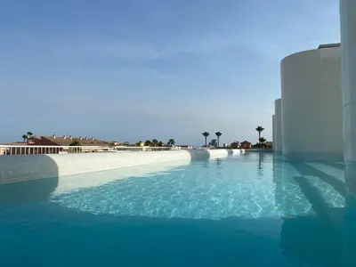 a large pool of blue water next to a building at Travel Habitat Playa Puzol con encanto in Puzol