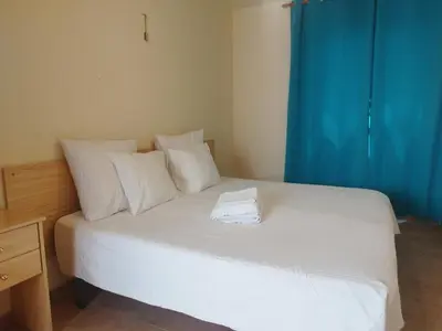 a white bed with white pillows and a blue curtain at Apartamento cerca del puerto deportivo 1 in Burriana
