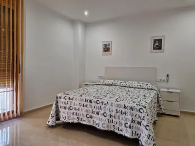 a bedroom with a bed with a black and white comforter at VIVIENDA La MERCED in El Puig