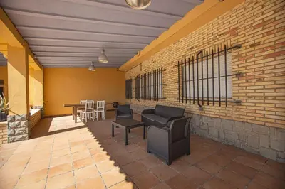 a patio with chairs and tables and a brick wall at Villa Azahar - Piscina - Barbacoa - Naturaleza in Valencia