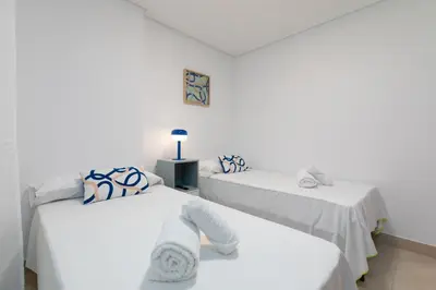 two beds in a room with white sheets and pillows at ApartUP Patacona Palm Beach II in Valencia