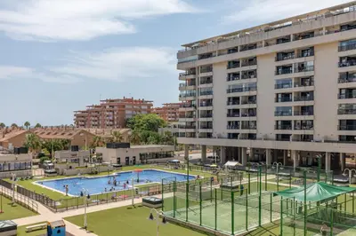 a building with a pool in front of a building at ApartUP Patacona Palm Beach II in Valencia