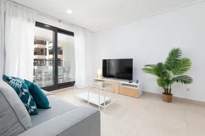 a living room with a couch and a flat screen tv at ApartUP Patacona Palm Beach II in Valencia