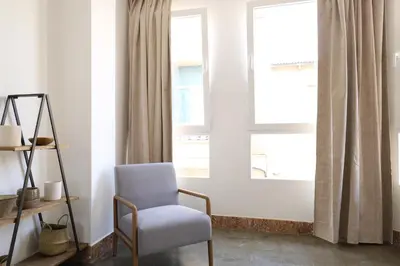 a living room with a chair and a window at Tradición y modernidad Casa de pueblo junto al mar in Puerto de Sagunto