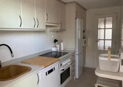 a kitchen with white cabinets and a sink and a refrigerator at Apartamento Premium frente al mar, en primera linea de playa in Cullera
