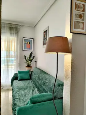a living room with a green couch and a lamp at Ático Playa Cullera in Cullera