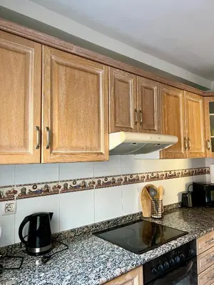 a kitchen with wooden cabinets and a counter top at Cozy Flat with City & Beach in Puerto de Sagunto