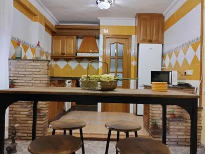 a kitchen with a large wooden counter with stools at Apartamento en la Sierra Espadan in Artana