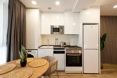 a kitchen with a table and a white refrigerator at Cortes Suites by Concept Flats in Valencia