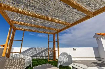 a pergola with white chairs and a blue sky at ViDa MaLu - Housevanlive in Sueca