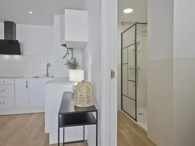 a white kitchen with a counter and a glass shower at Estudio Temporal a 2' de la playa de Sagunto A2 in Puerto de Sagunto