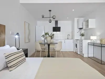 a white kitchen with a table and a dining room at Estudio Temporal a 2' de la playa de Sagunto A2 in Puerto de Sagunto