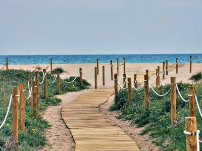 a wooden path leading to the beach at Oasis Junto al Mar a 2 minutos de playa Sagunto A6 in Puerto de Sagunto