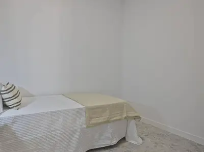 a bed in a room with a white wall at Oasis Junto al Mar a 2 minutos de playa Sagunto A6 in Puerto de Sagunto